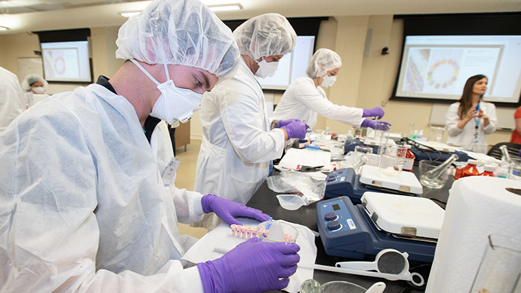 Pharmacy students mixing substances together during a lab activity.